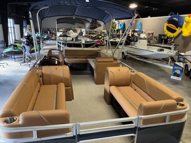 Slide: The Image of 2025 Tahoe Pontoon SP 2180 CR with tan seating, displayed in a showroom with various boats. - 11