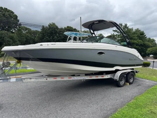 The Image of 2023 NauticStar 243 DC boat on trailer, parked outdoors under cloudy sky. - 1