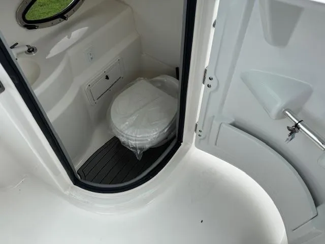 Slide: The Image of 2023 NauticStar 243 DC boat interior with compact marine toilet and sleek design. - 7