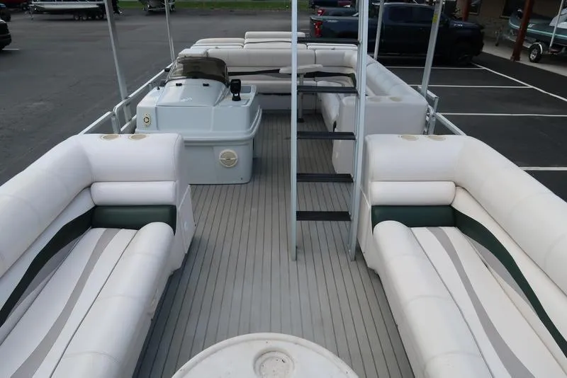Slide: The Image of 2001 Harris Super Sunliner 240 pontoon boat with spacious seating and helm, parked in a lot. - 13