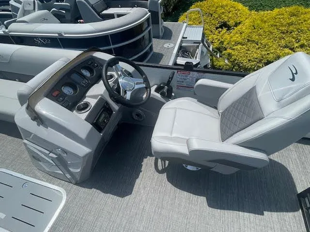 Slide: The Image of 2024 Bennington 23 SXSWB boat interior with steering console and plush seating. - 4