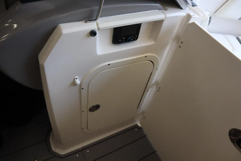 Slide: The Image of 2023 Chaparral 23 Surf boat interior with storage compartment and control panel. - 12