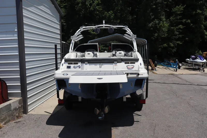 Slide: The Image of 2023 Chaparral 23 Surf boat parked near a metal building, rear view. - 2