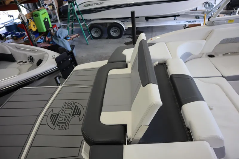 Slide: The Image of 2023 Chaparral 23 Surf boat interior with gray and white seating in a showroom. - 31