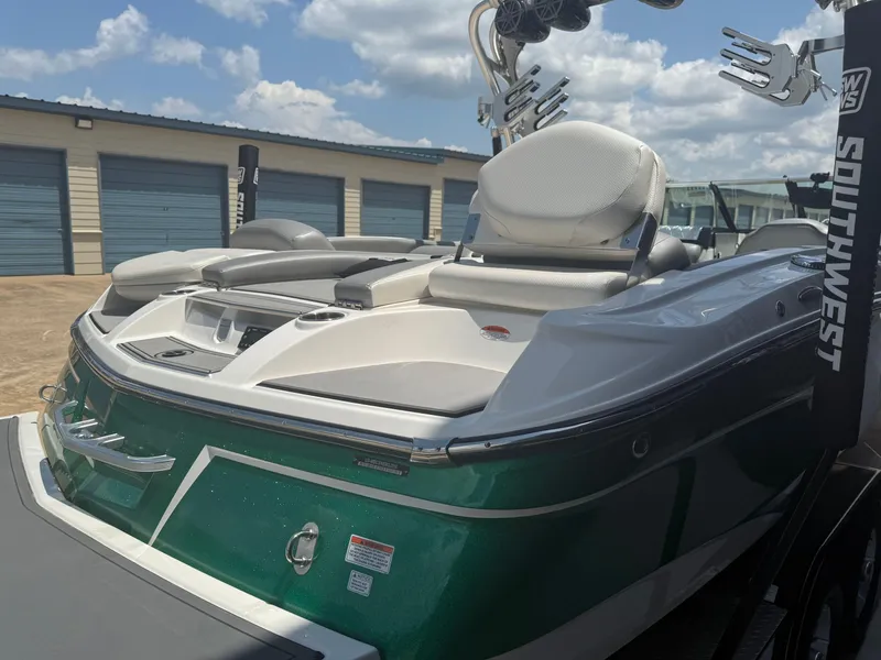 Slide: The Image of 2016 MasterCraft X46 boat with green hull, parked near storage units under a cloudy sky. - 4