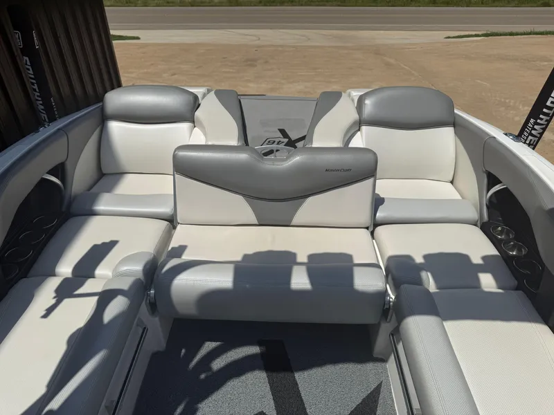 Slide: The Image of 2016 MasterCraft X46 boat interior with white and gray seating, cup holders, and spacious layout. - 8