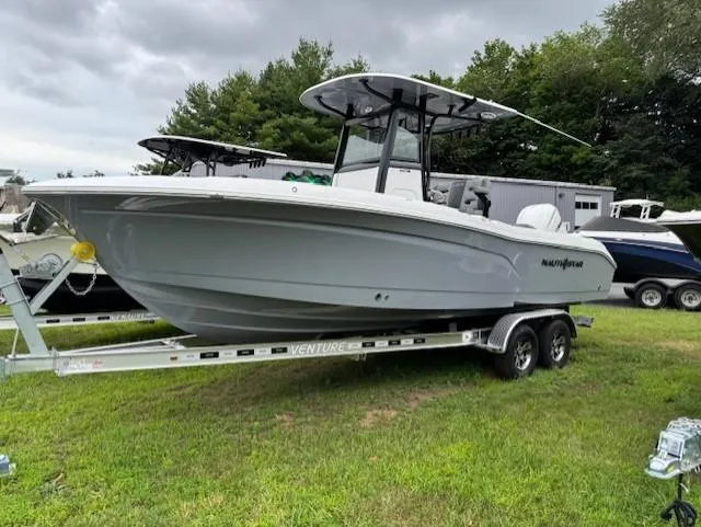 Slide: The Image of 2025 NauticStar 242 Offshore boat on trailer, parked on grass under cloudy sky. - 5
