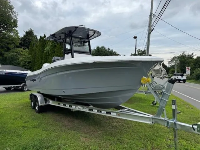 Slide: The Image of 2025 NauticStar 242 Offshore boat on trailer, parked on grass beside a road. - 6
