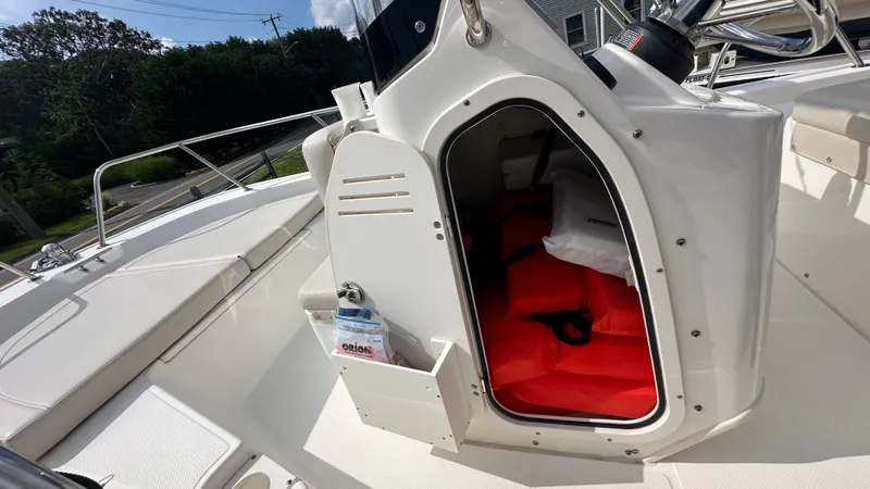 Slide: The Image of 2022 Boston Whaler 150 Montauk boat storage compartment with safety gear and life jackets. - 16