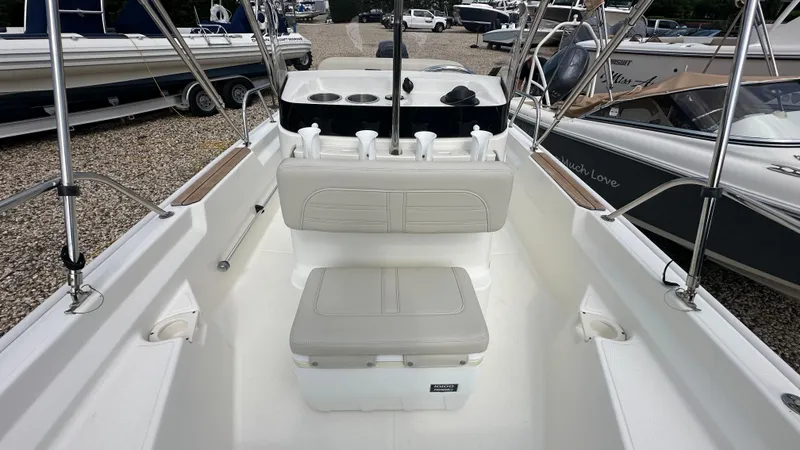 Slide: The Image of 2022 Boston Whaler 150 Montauk interior with seating and console, displayed outdoors. - 18