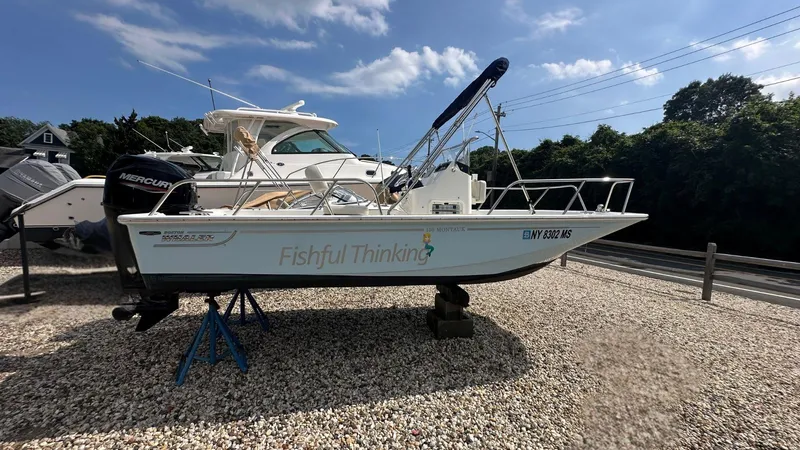 Slide: The Image of 2022 Boston Whaler 150 Montauk boat named "Fishful Thinking" on display outdoors. - 2