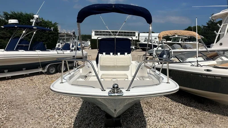 Slide: The Image of 2022 Boston Whaler 150 Montauk boat with blue canopy, displayed on gravel lot. - 24