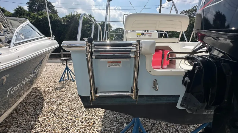 Slide: The Image of 2022 Boston Whaler 150 Montauk boat with ladder and outboard motor, displayed on stands. - 6