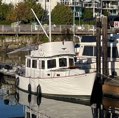 The Image of 1974 Willard Nomad boat docked in a marina, reflecting on calm water. - 0