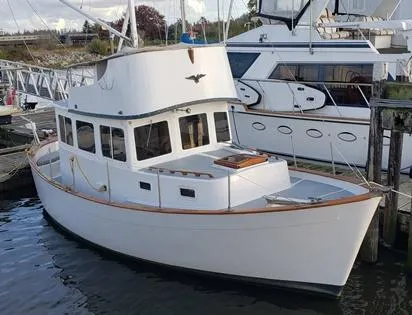 Slide: The Image of 1974 Willard Nomad boat docked at a marina, featuring classic design and white exterior. - 1