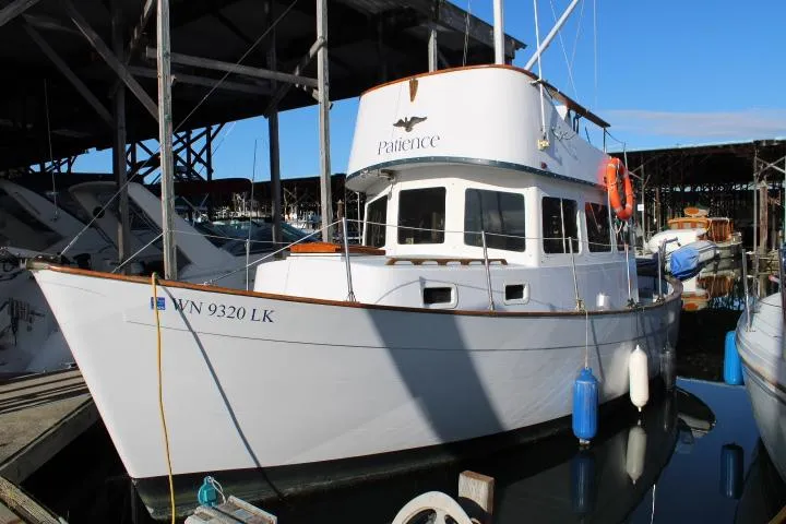 Slide: The Image of 1974 Willard Nomad boat docked, featuring "Patience" on the cabin, with clear blue sky. - 2