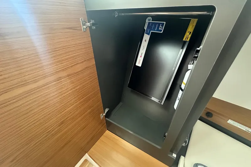 Slide: The Image of Cabinet interior on 2026 Tiara Yachts 34 LS, featuring a mounted screen and fire extinguisher. - 28