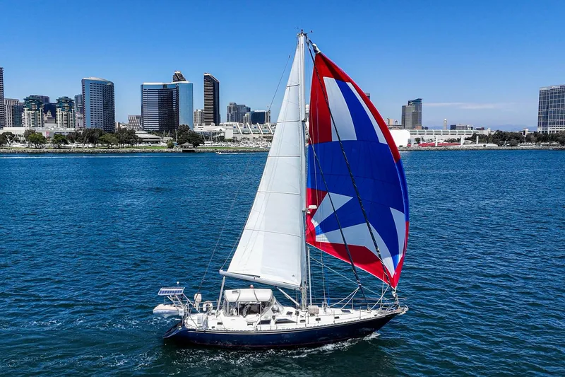 Slide: The Image of Sailboat Hylas 49 (2001) with colorful spinnaker sailing near city skyline. - 2