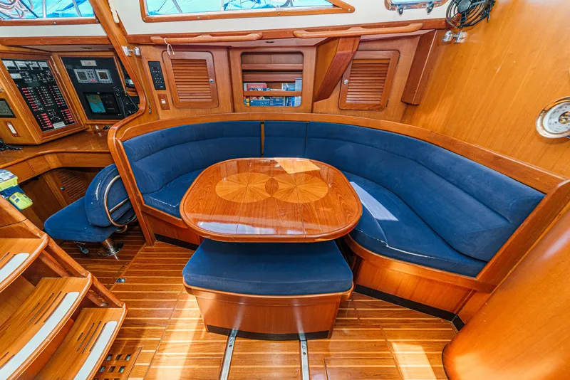 Slide: The Image of Luxurious 2001 Hylas 49 yacht interior with blue cushioned seating and polished wooden table. - 25