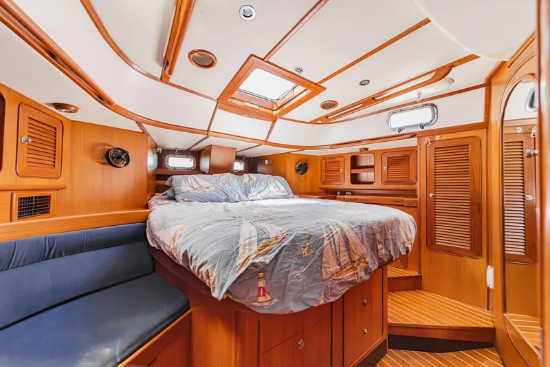 Slide: The Image of Luxurious cabin interior of a 2001 Hylas 49 yacht with wooden finishes and cozy bedding. - 36