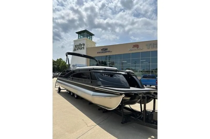 Slide: The Image of 2025 Bennington 25 QSBA pontoon boat displayed outside dealership. - 0