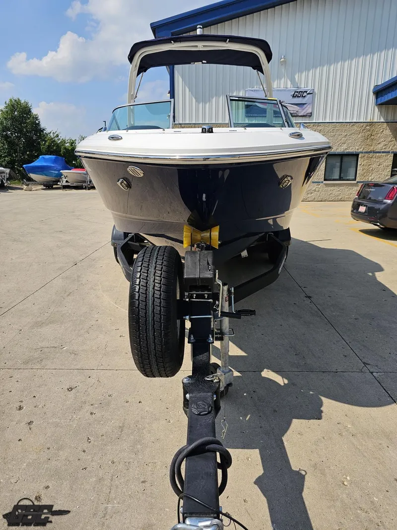 Slide: The Image of 2022 Chaparral 21 SSi boat on trailer, parked outside a building under a clear sky. - 16