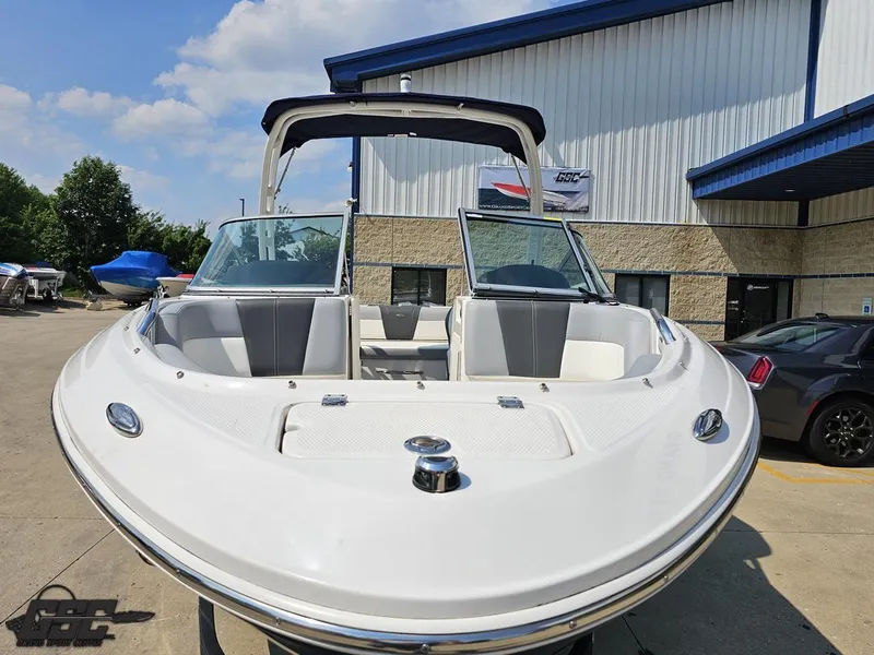 Slide: The Image of 2022 Chaparral 21 SSi boat with open bow, parked outside a building. - 17