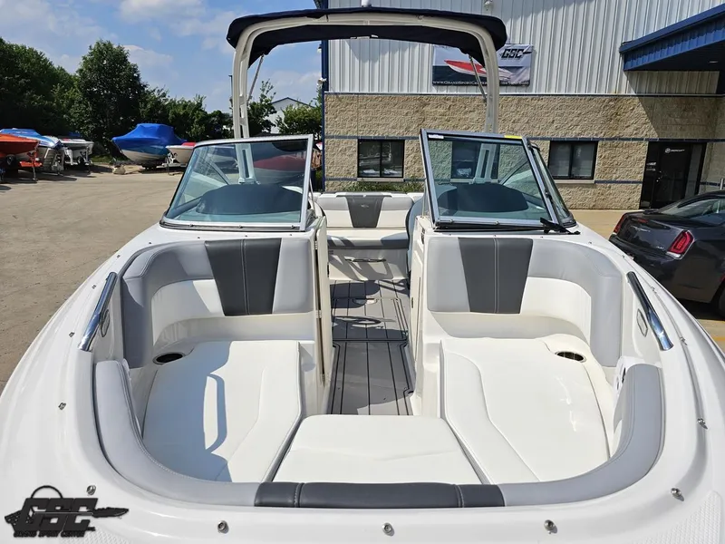 Slide: The Image of 2022 Chaparral 21 SSi boat interior with open bow seating and windshield, parked outdoors. - 18