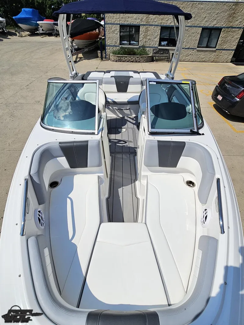 Slide: The Image of 2022 Chaparral 21 SSi boat interior with seating and windshield, docked outdoors. - 19