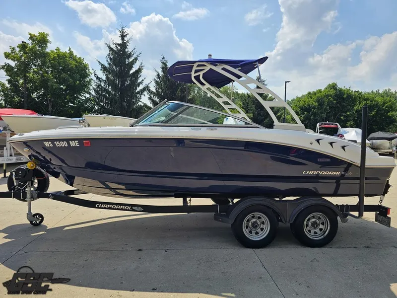 Slide: The Image of 2022 Chaparral 21 SSi boat on trailer, parked outdoors under a partly cloudy sky. - 25