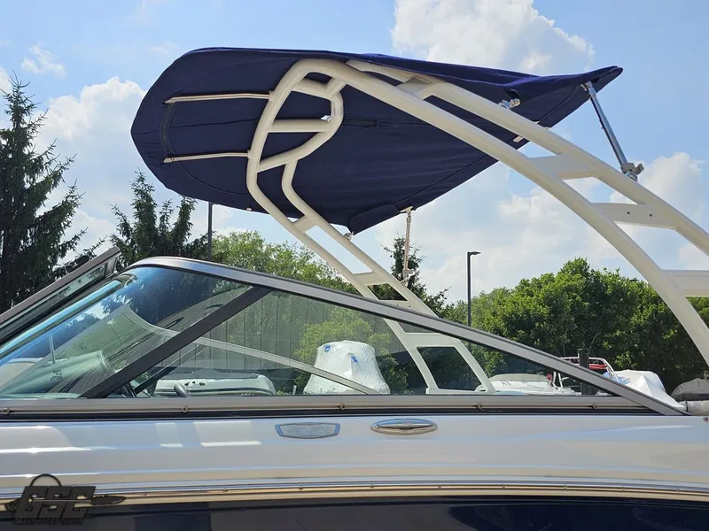 Slide: The Image of 2022 Chaparral 21 SSi boat with blue canopy, side view under clear sky. - 28