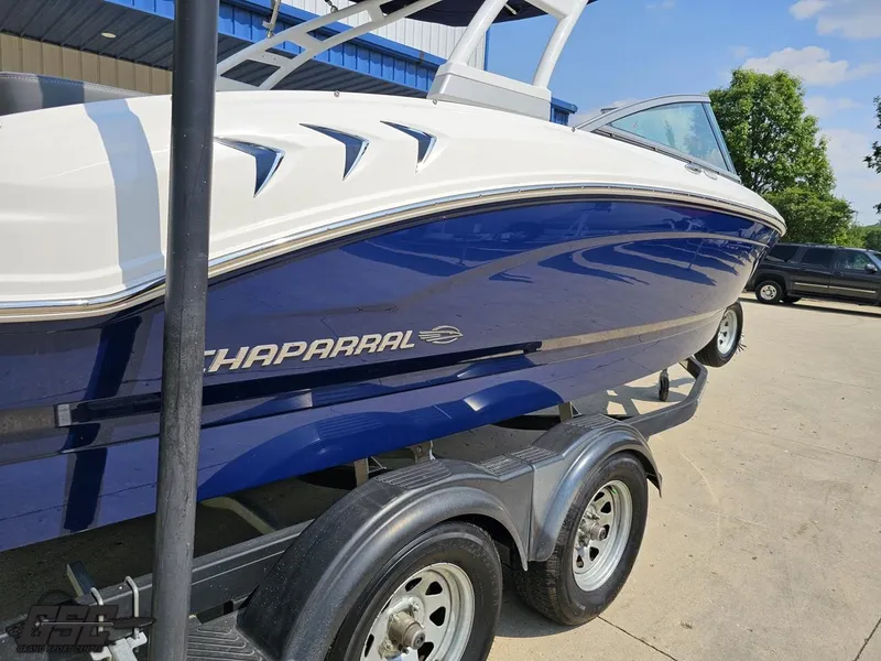 Slide: The Image of 2022 Chaparral 21 SSi boat on trailer, blue and white design, parked outdoors. - 39