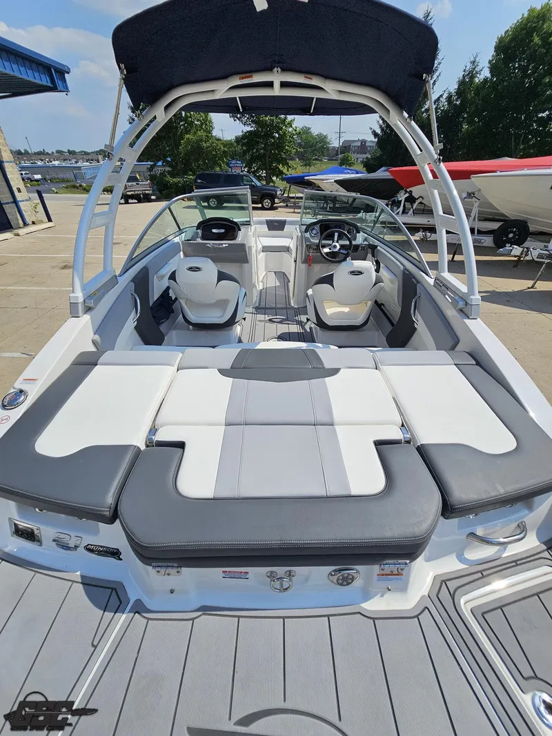 Slide: The Image of 2022 Chaparral 21 SSi boat interior with seating and steering wheel, docked outdoors. - 46