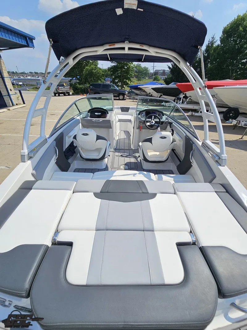 Slide: The Image of 2022 Chaparral 21 SSi boat interior with seating and steering wheel, docked outdoors. - 47