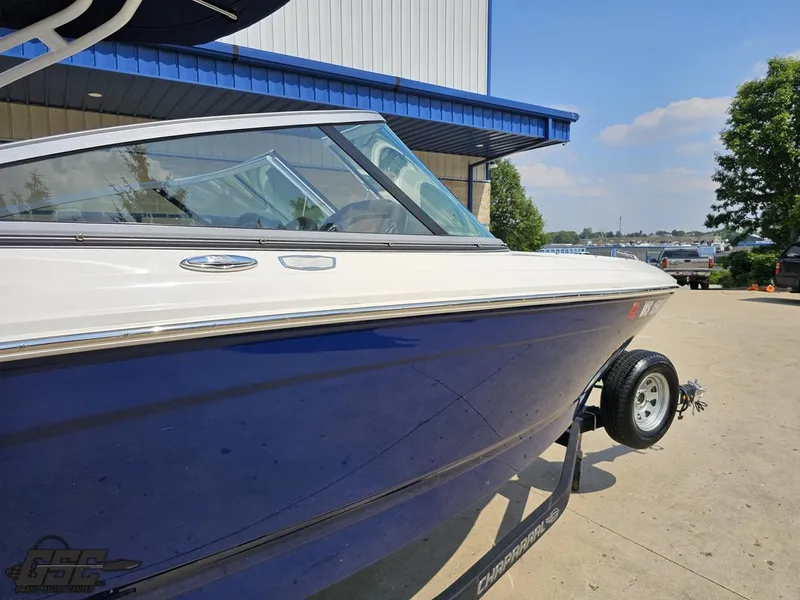 Slide: The Image of 2022 Chaparral 21 SSi boat with blue hull on trailer, parked outdoors. - 9