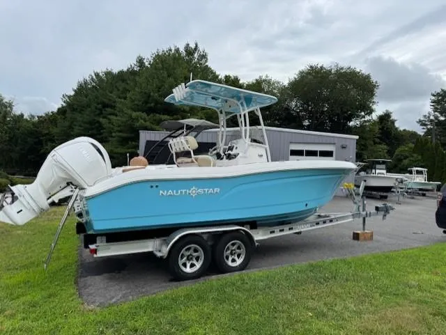 The Image of 2025 NauticStar 222L Offshore boat on trailer, parked outdoors near a building. - 1