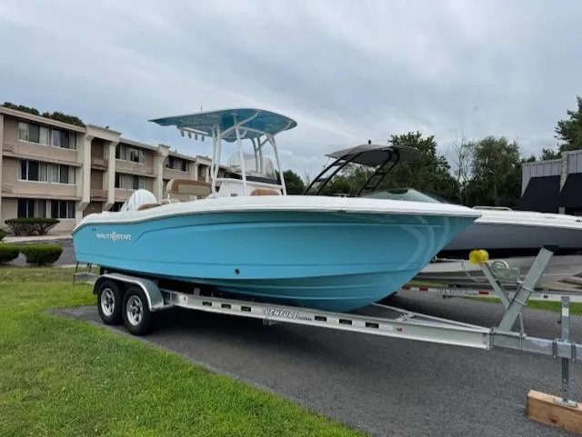 Slide: The Image of 2025 NauticStar 222L Offshore boat on trailer, parked outdoors near buildings. - 2