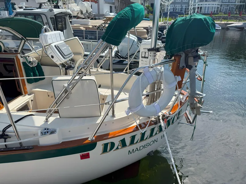 Slide: The Image of 1993 Pacific Seacraft Crealock 34 sailboat docked, featuring green covers and a lifebuoy. - 3