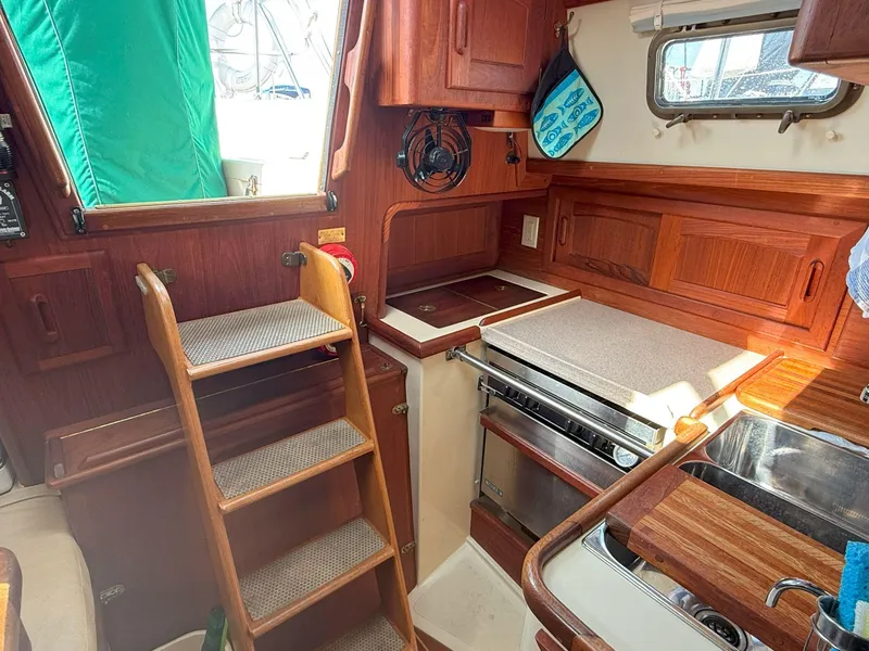 Slide: The Image of Cozy galley of 1993 Pacific Seacraft Crealock 34 sailboat with wooden cabinetry and compact design. - 38