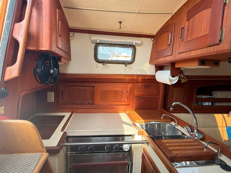 Slide: The Image of Interior of 1993 Pacific Seacraft Crealock 34 sailboat, featuring a compact kitchen with wooden cabinetry. - 39
