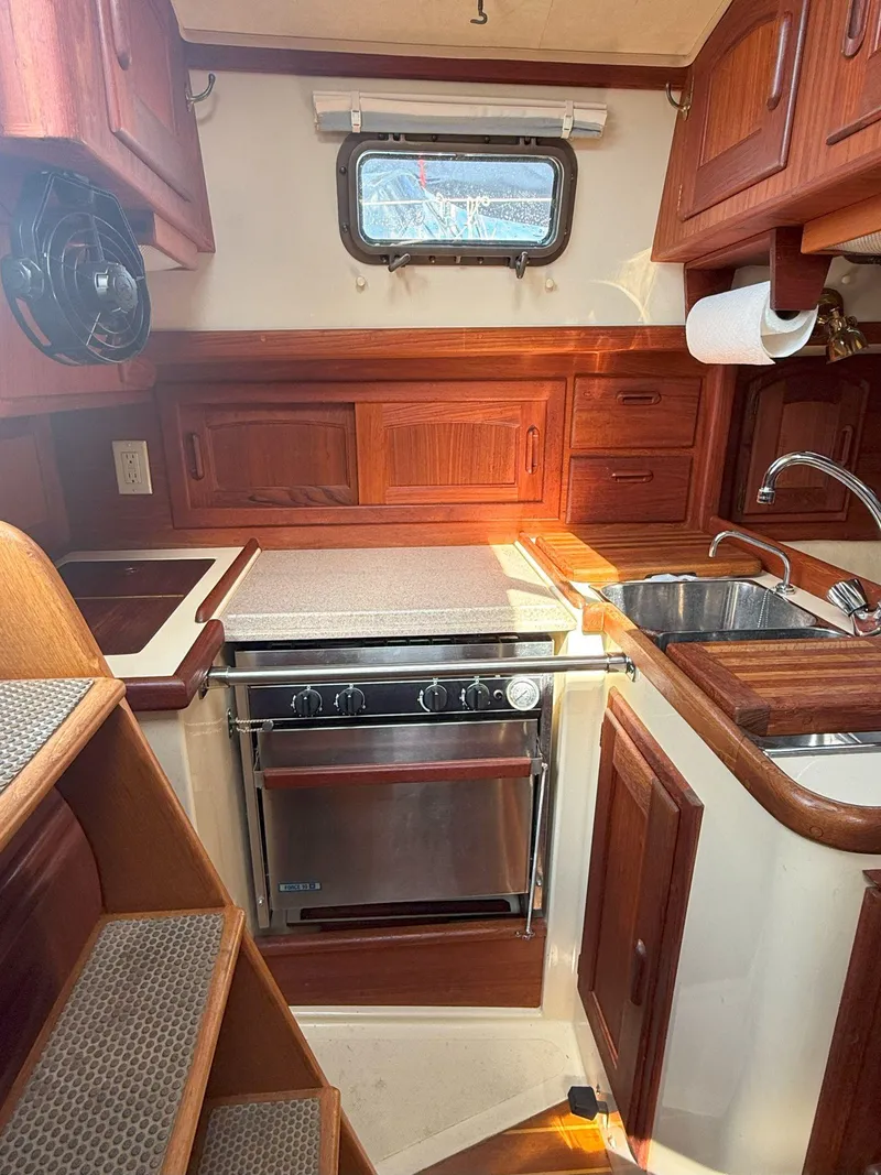 Slide: The Image of Cozy 1993 Pacific Seacraft Crealock 34 yacht kitchen with wood cabinetry and stainless steel appliances. - 40