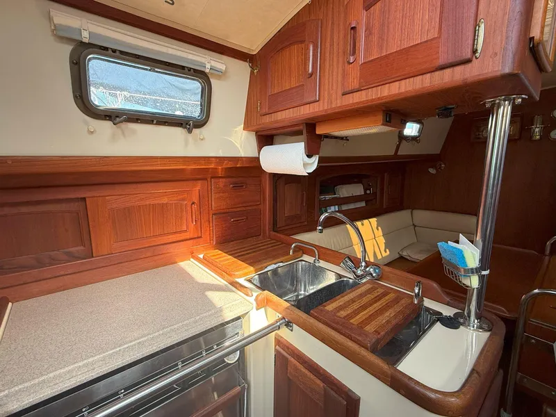 Slide: The Image of Cozy 1993 Pacific Seacraft Crealock 34 yacht interior with wooden cabinetry and compact kitchen. - 42