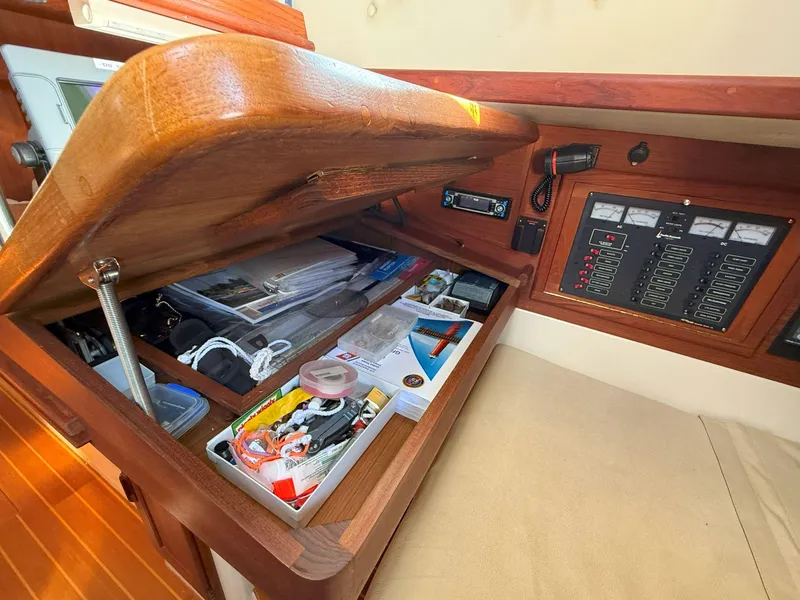 Slide: The Image of Navigation station of 1993 Pacific Seacraft Crealock 34 with open storage compartment and control panel. - 48