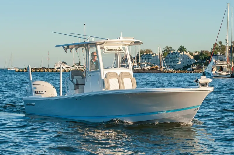 The Image of 2026 Regulator 26XO boat cruising on a calm harbor with scenic background. - 0