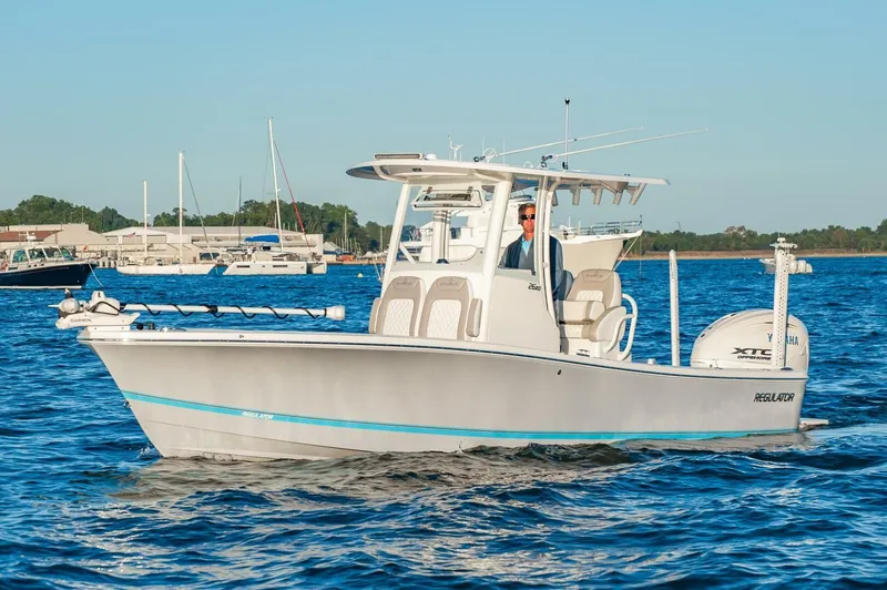 Slide: The Image of 2026 Regulator 26XO boat cruising on a calm blue waterway. - 1