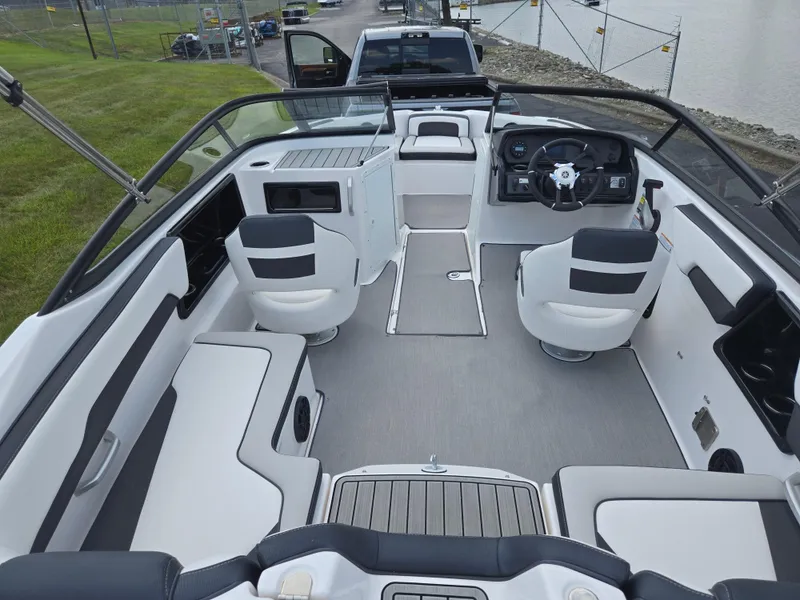 Slide: The Image of 2021 Yamaha Boats SX195 interior with modern seating and steering, docked near a grassy area. - 10
