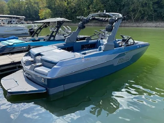 Slide: The Image of 2023 Malibu M240 boat docked on a serene lake, showcasing sleek design and modern features. - 4