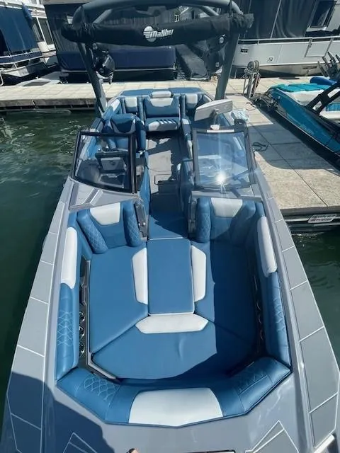 Slide: The Image of 2023 Malibu M240 boat with blue and white interior, docked at a marina. - 6