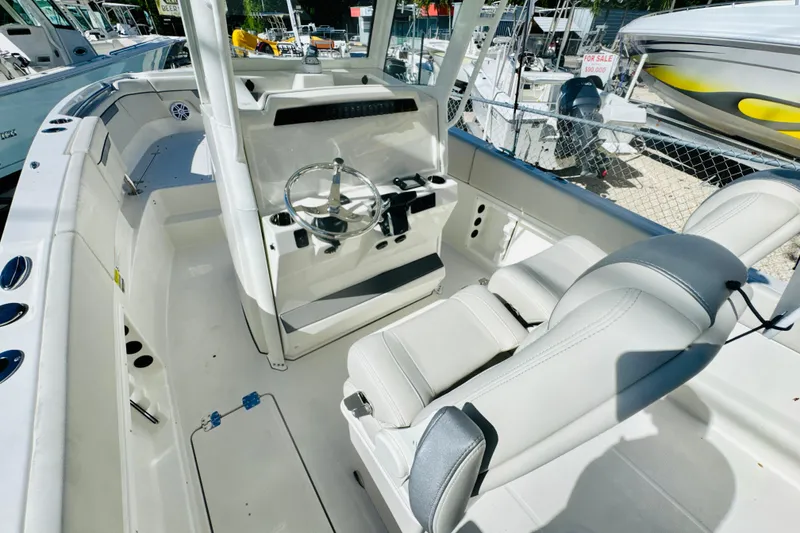 Slide: The Image of 2026 Sailfish 252 CC boat interior with steering wheel and seating, displayed at a marina. - 11