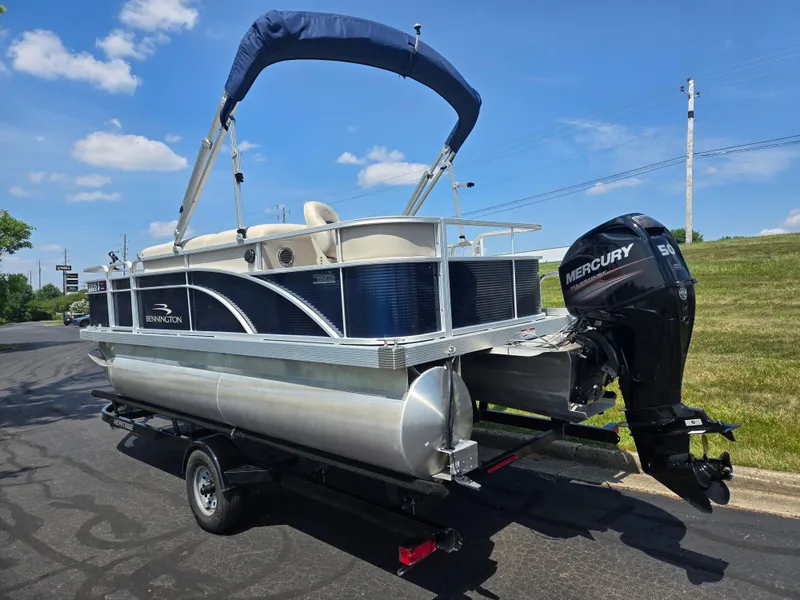 Slide: The Image of 2019 Bennington 188 SFV pontoon boat with Mercury 50 engine on trailer, under blue sky. - 3